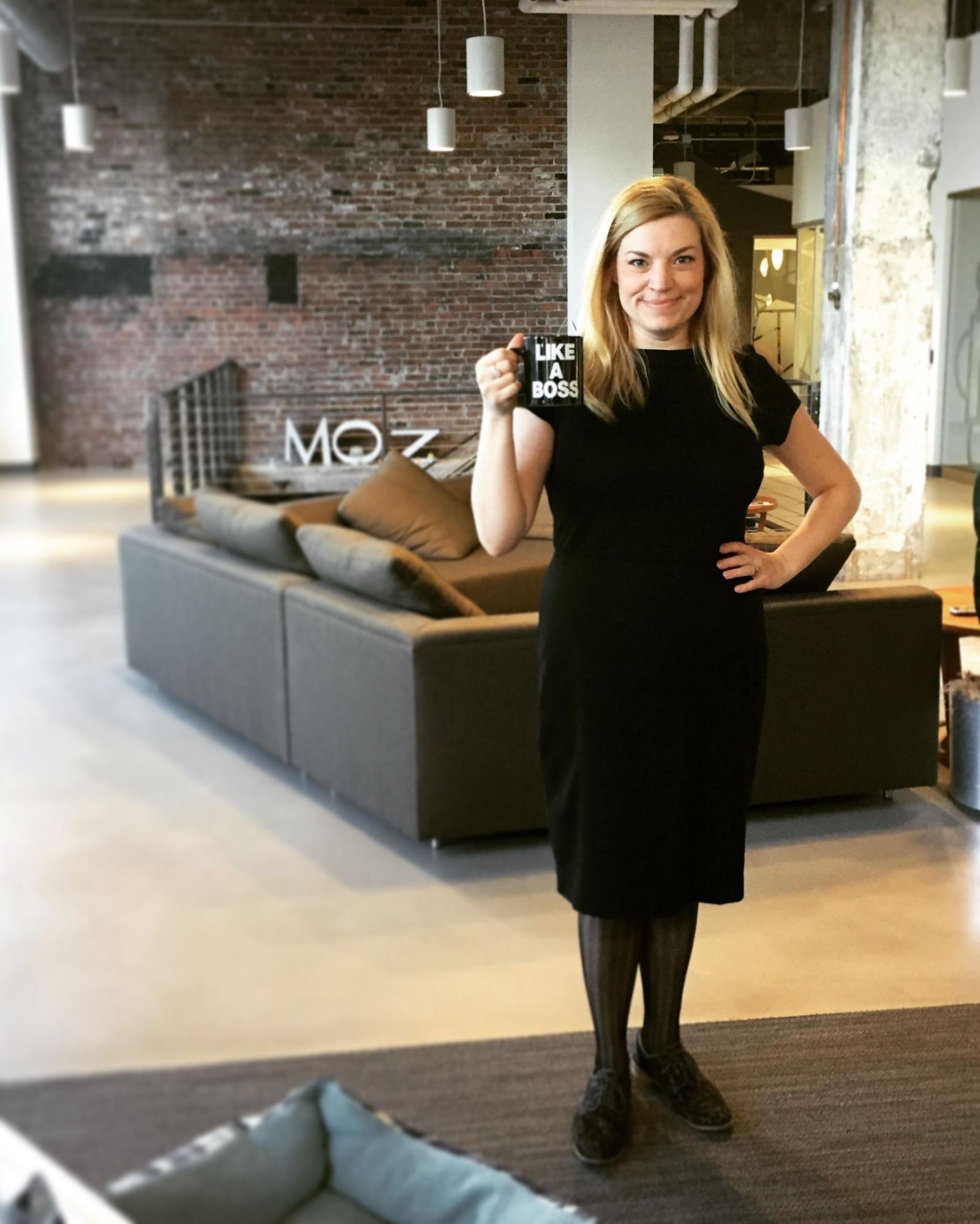 Sarah Bird posing in the Moz offices with her 'Like a Boss' mug.