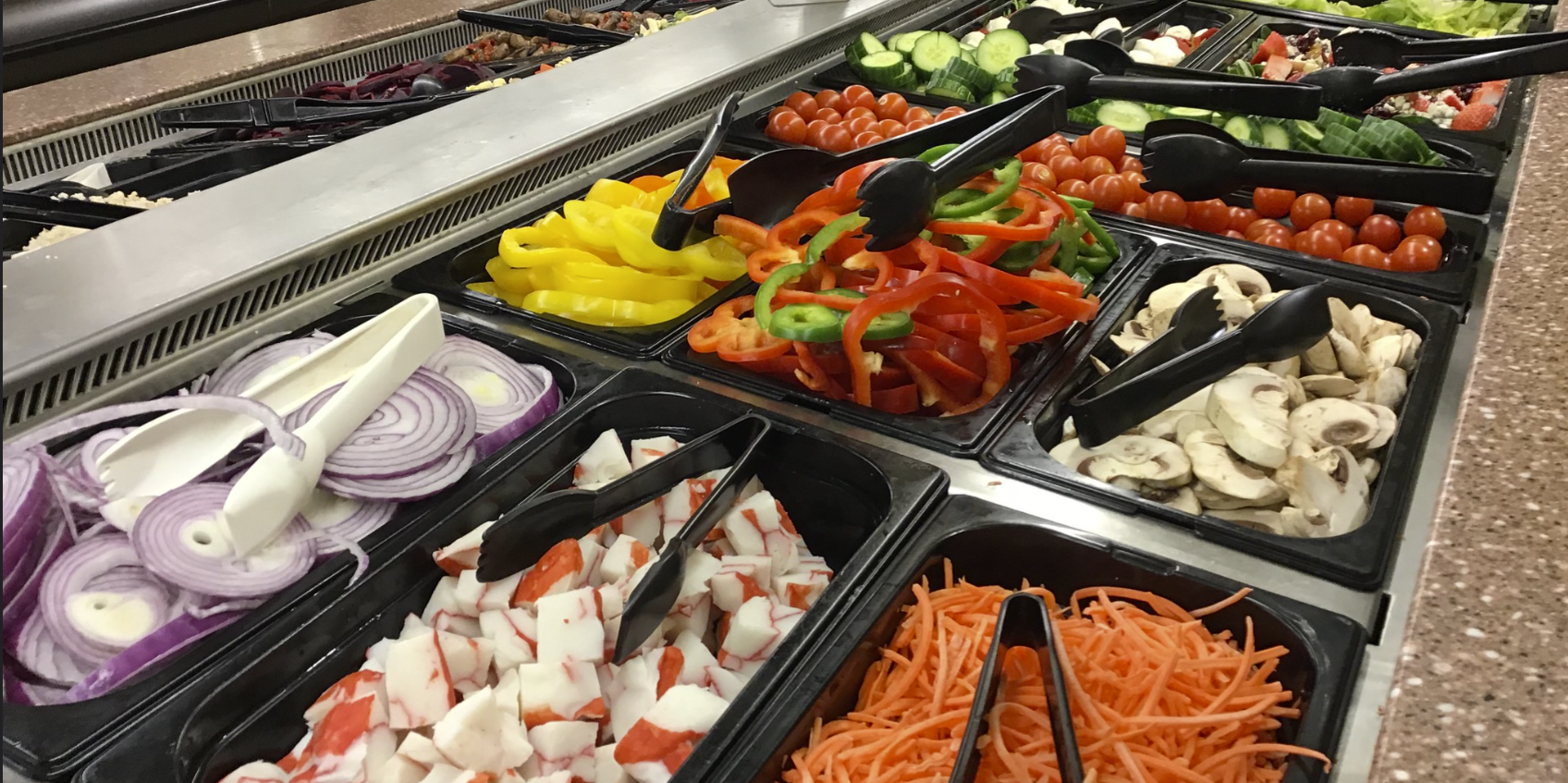 Image of a loaded salad bar with lots of options