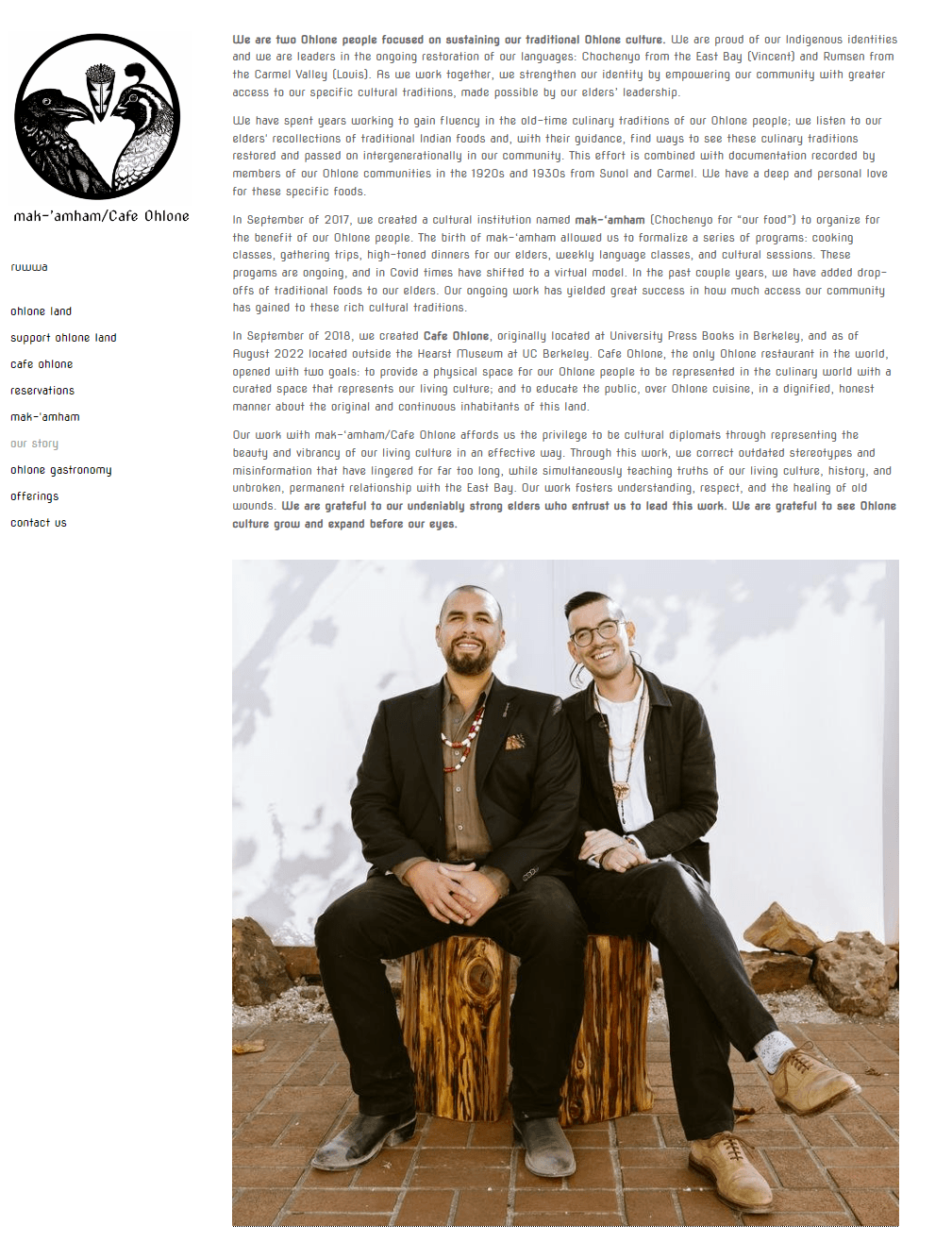 An informal photo of two business owners seated on log stumps and smiling.